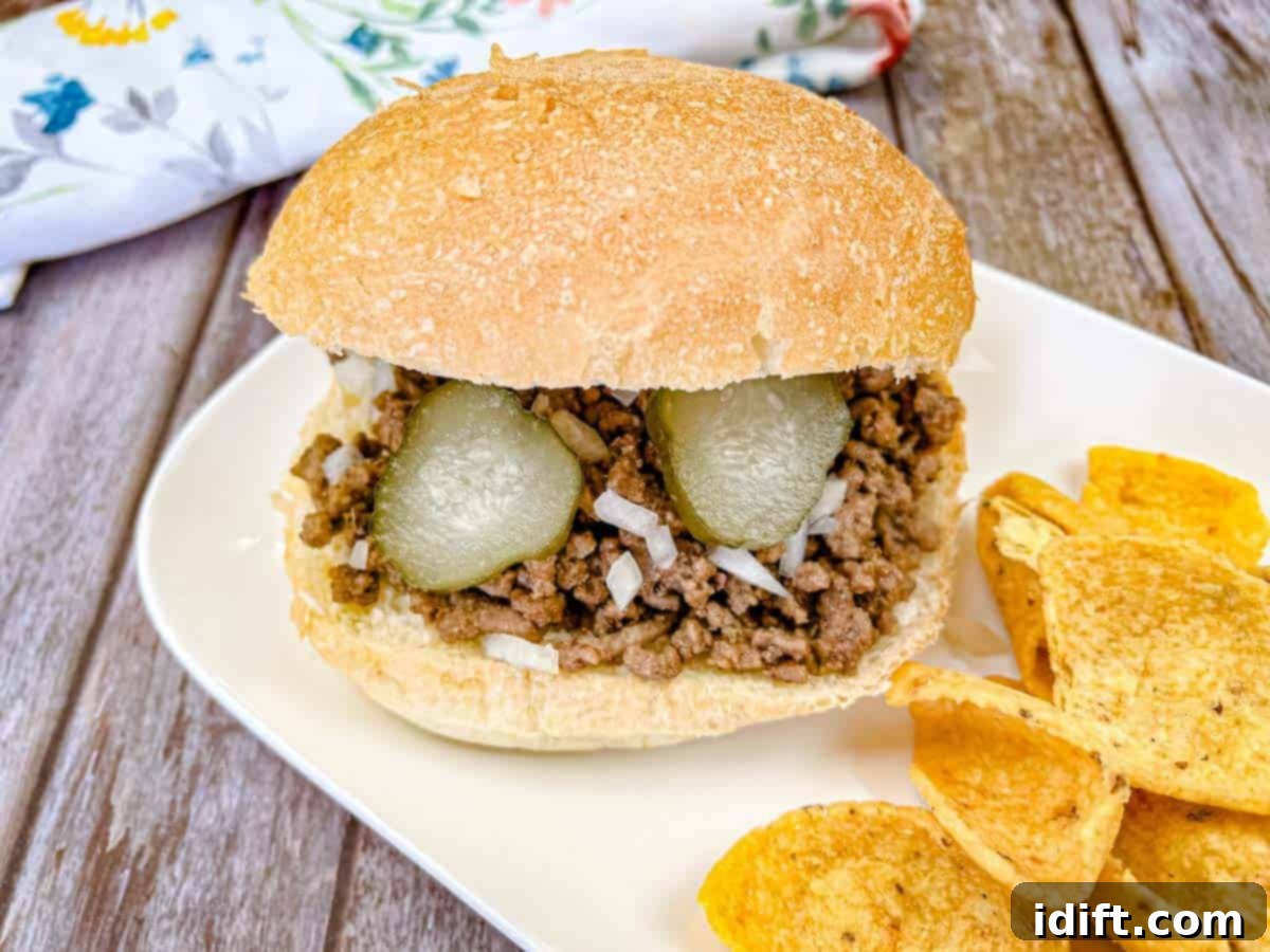 17 Ground Beef Recipes Too Good For Cookbooks 19 Copycat Maid-Rite Loose Meat Sandwich on a white plate with potato chips, ready to be enjoyed.