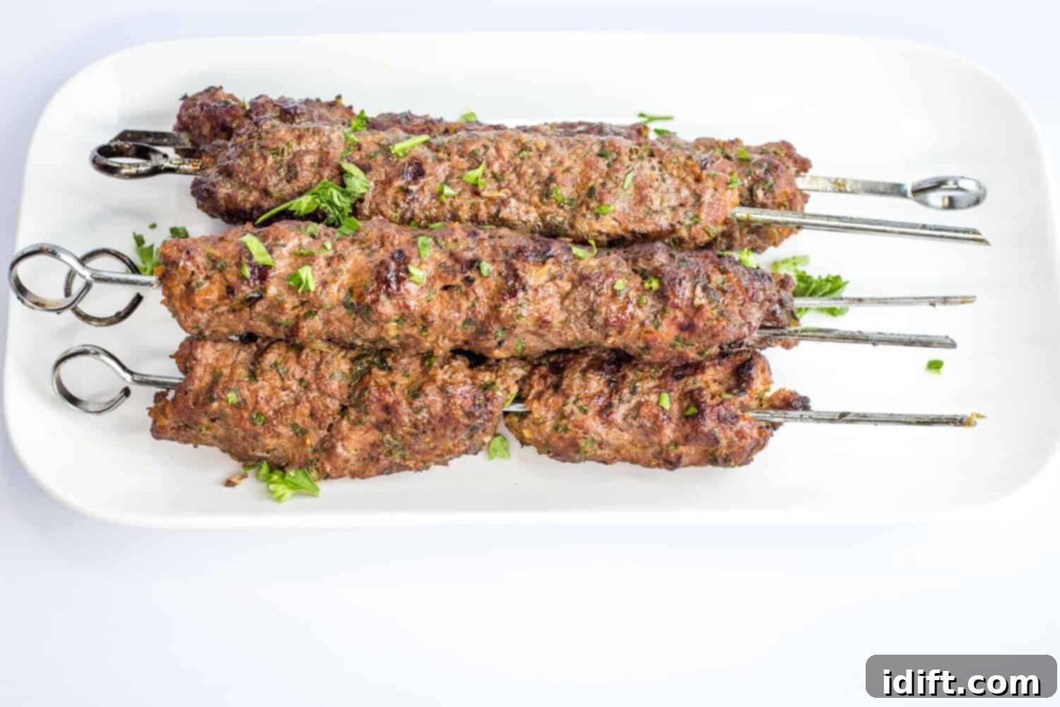 17 Ground Beef Recipes Too Good For Cookbooks 8 Stacked Kefta Beef Kabobs, perfectly grilled and seasoned, on a rustic white platter.
