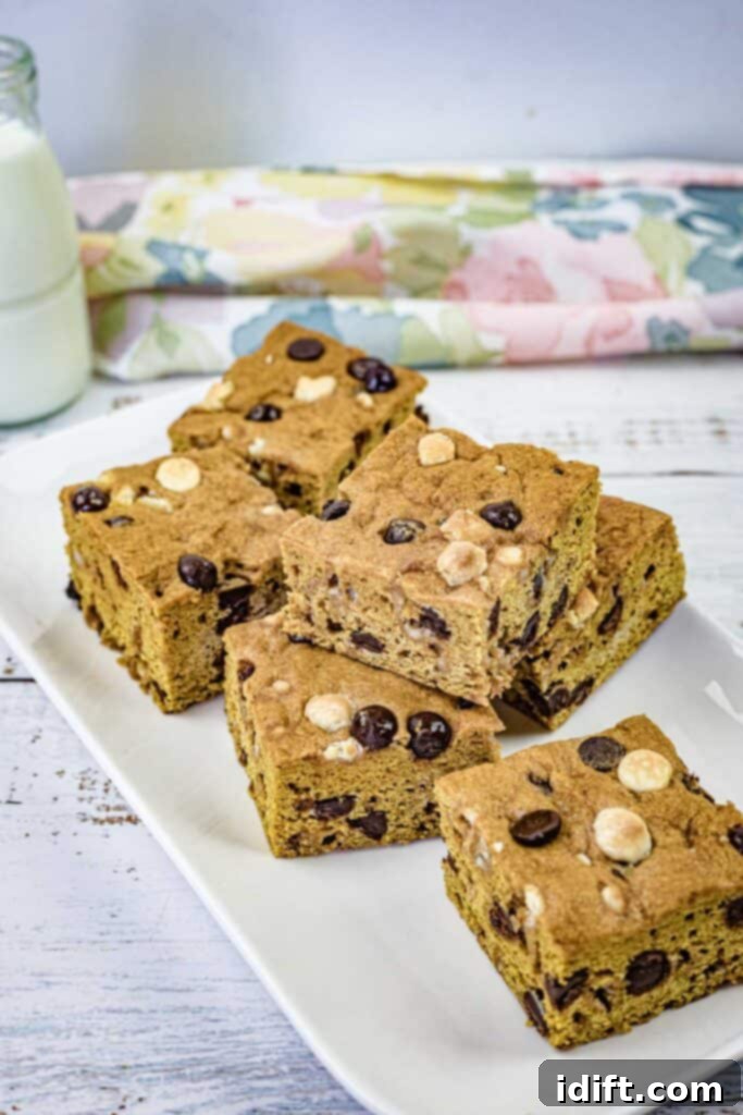 Pieces of pumpkin blondies on a white rectangular plate, showcasing their inviting texture and golden-brown crust.