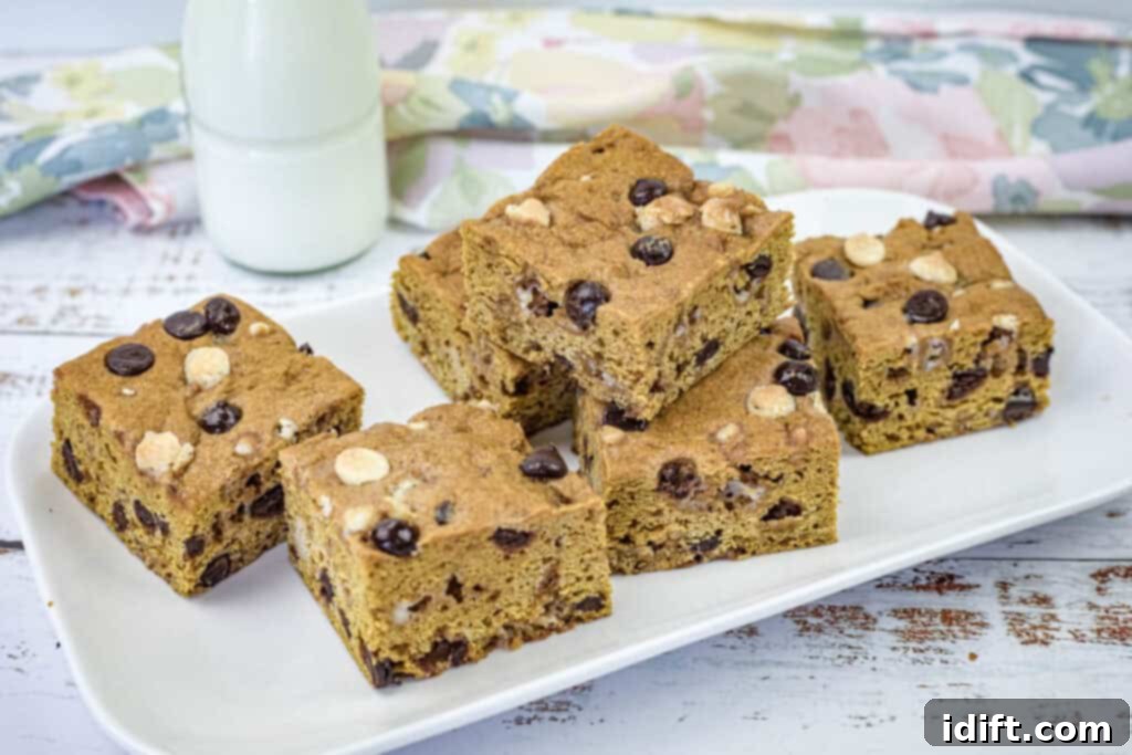A pristine white rectangular plate adorned with several tempting pieces of pumpkin blondies, perfectly arranged for serving.