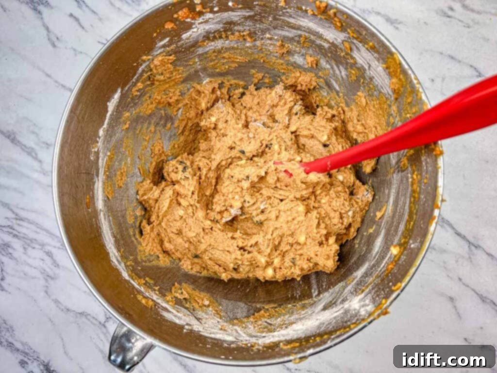 Dry ingredients being folded into the wet batter until just combined, with a wooden spoon.