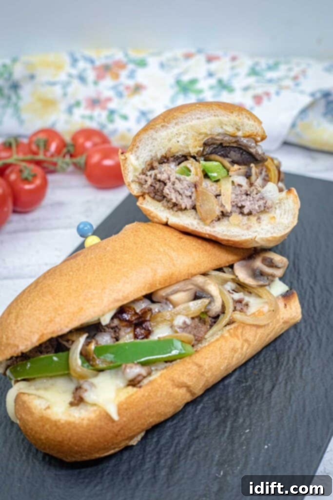 Elevated Ground Beef Philly Cheesesteak 2 Halves of Ground Beef Philly Cheesesteak on a slate plate.