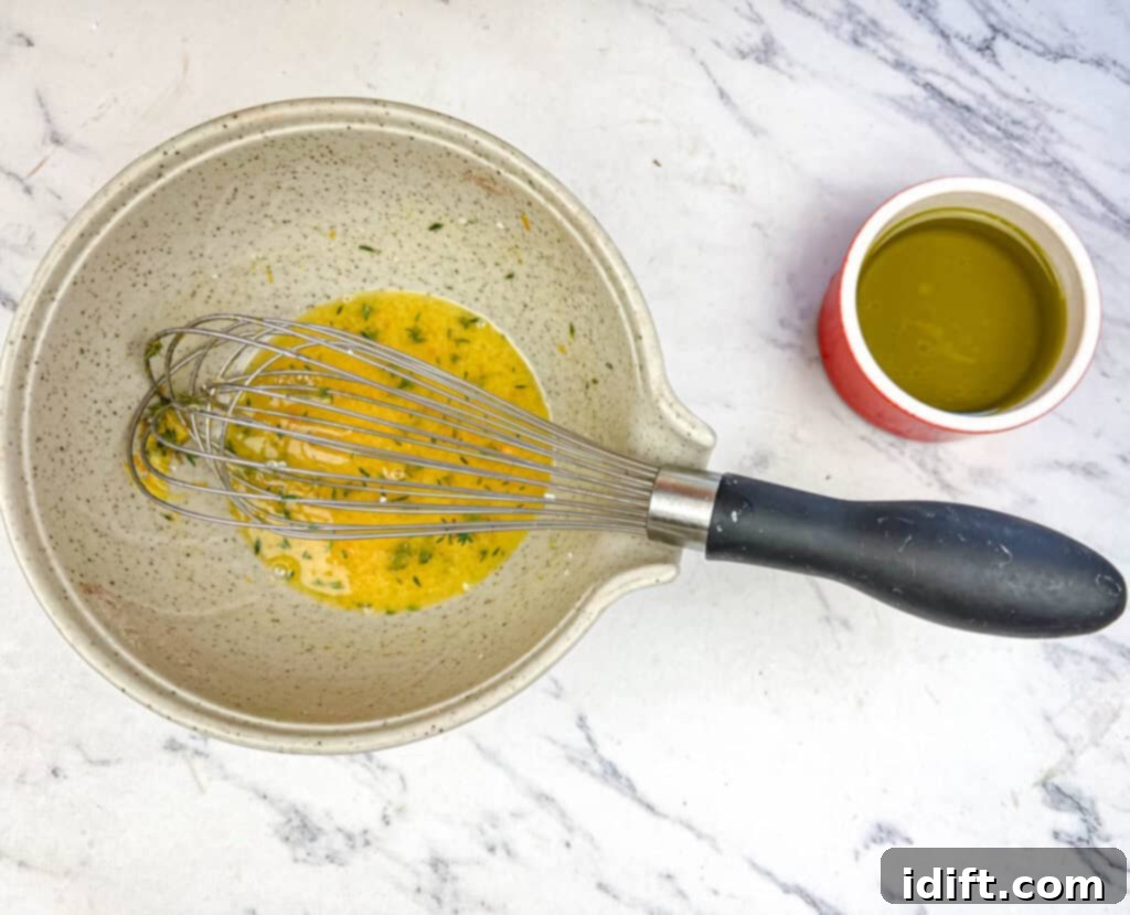 Golden Autumn Salmon Bowl 11 A small bowl containing orange juice, lemon juice, mustard powder, honey, orange zest, and salt, being vigorously whisked to create the base of the zesty citrus dressing.