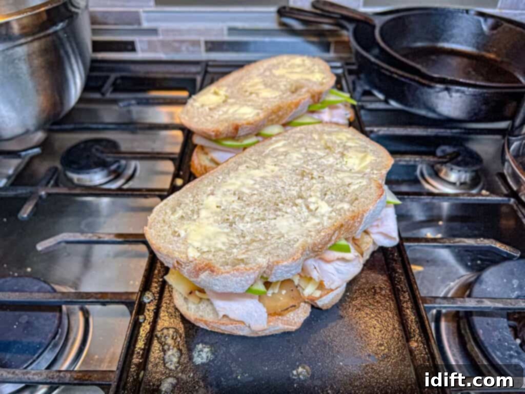 Close-up of a Turkey & Apple Grilled Cheese sizzling on a griddle, achieving a perfect golden crust.