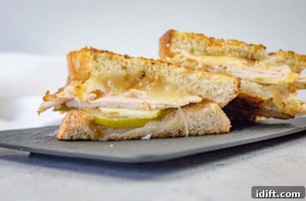 A beautifully presented, sliced Turkey & Apple Grilled Cheese on a plate, ready to be enjoyed.