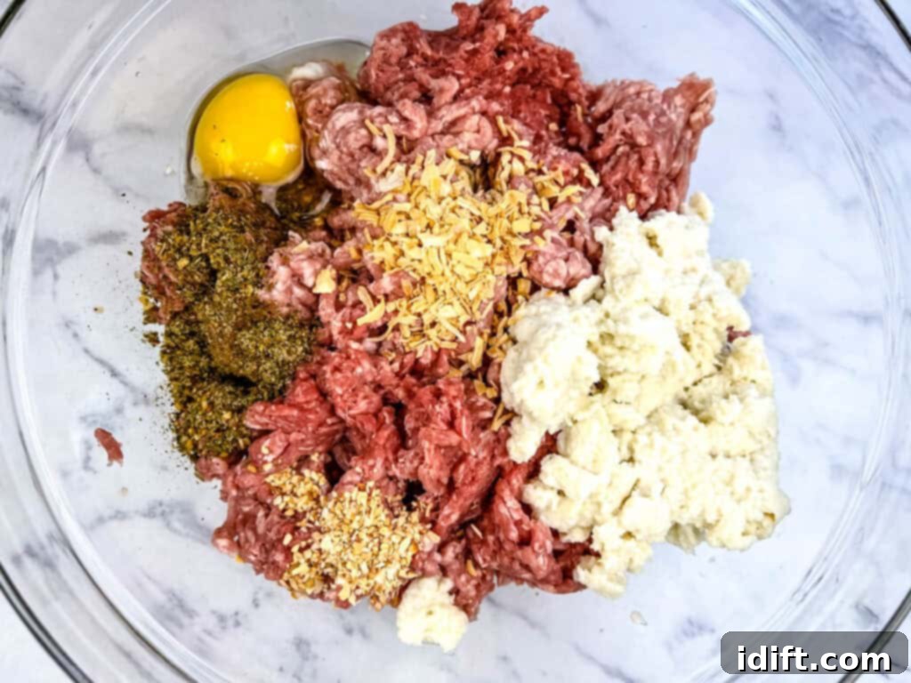 A person's hands gently mixing ground meat, soaked bread, and seasonings in a large mixing bowl with a spatula, ensuring even distribution without overworking.