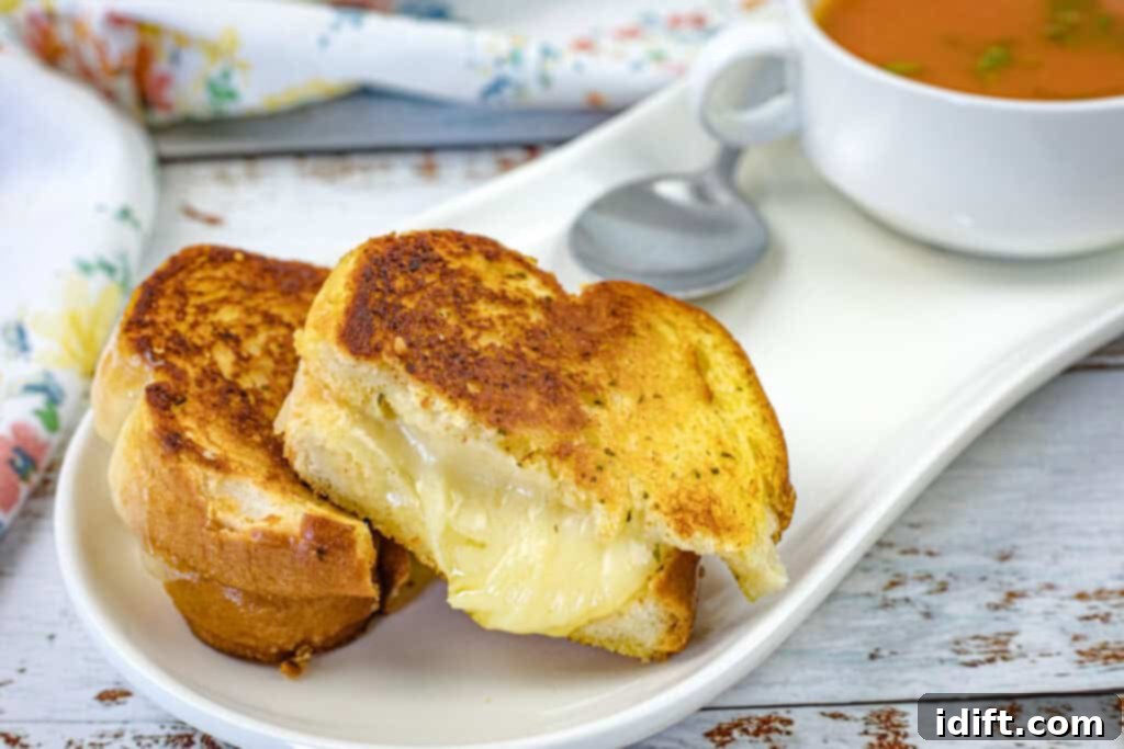 A single Garlic Bread Grilled Cheese sandwich, cut in half, presented on a white plate, ready to be enjoyed.