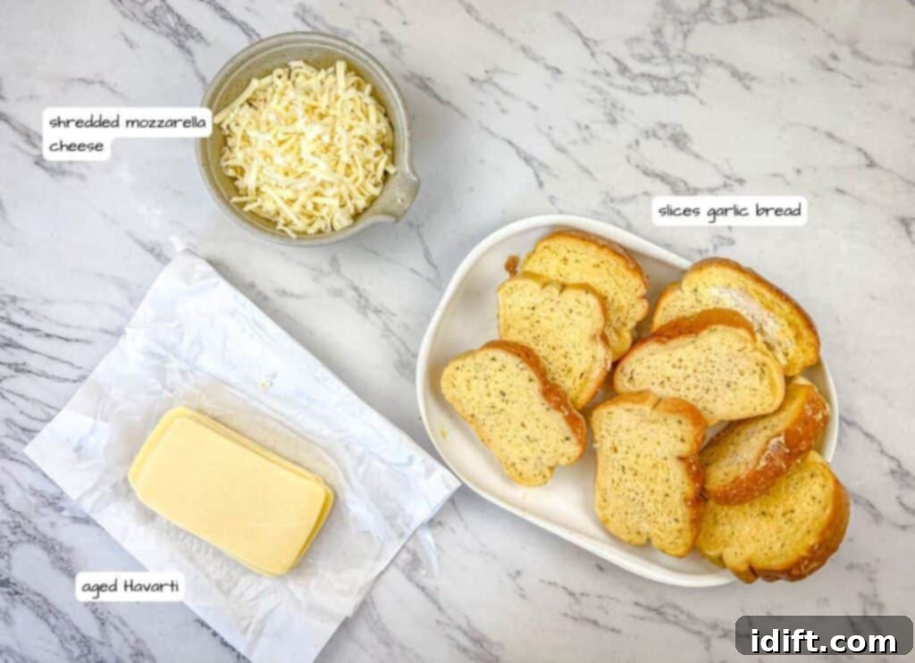 Clearly labeled ingredients for Garlic Bread Grilled Cheese, including garlic bread, sliced Havarti, and shredded mozzarella, laid out on a clean surface.