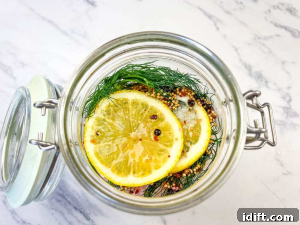 The jar is filled with cooked shrimp, marinade, and topped with the remaining dill, onion, and lemon, ready for pickling.