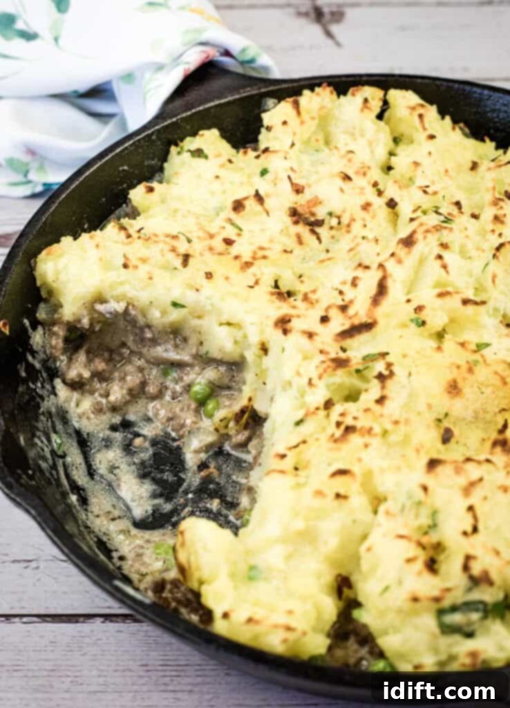 A Skillet Stroganoff Pie with a small portion missing, showing the creamy beef base and golden potato topping.