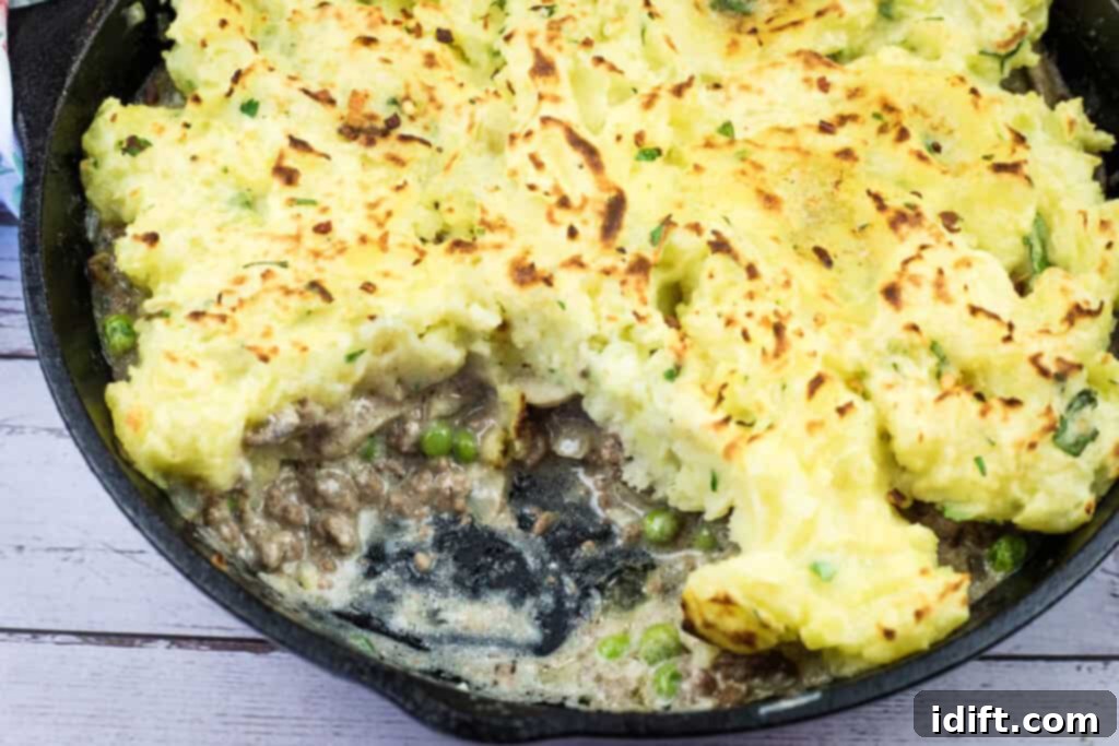 A Skillet Stroganoff Pie with a portion removed, showcasing the layers of potato and creamy beef stroganoff, on a serving board.