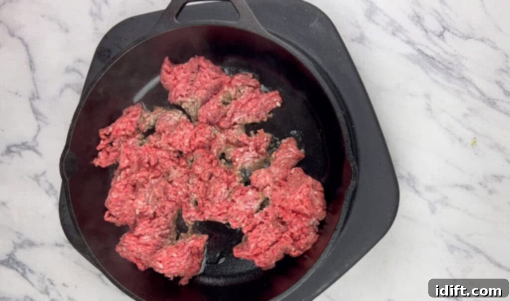 Ground beef browning in an oven-proof skillet over medium heat.