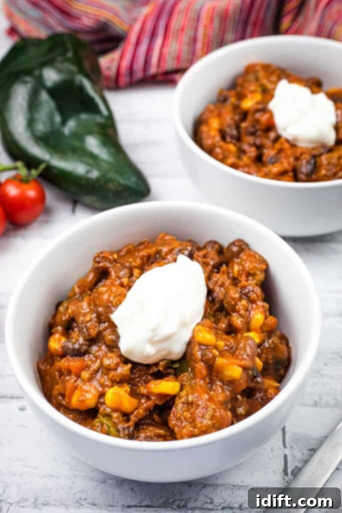 Two bowls of Slow Cooker Southwestern Chili, garnished and ready to serve.