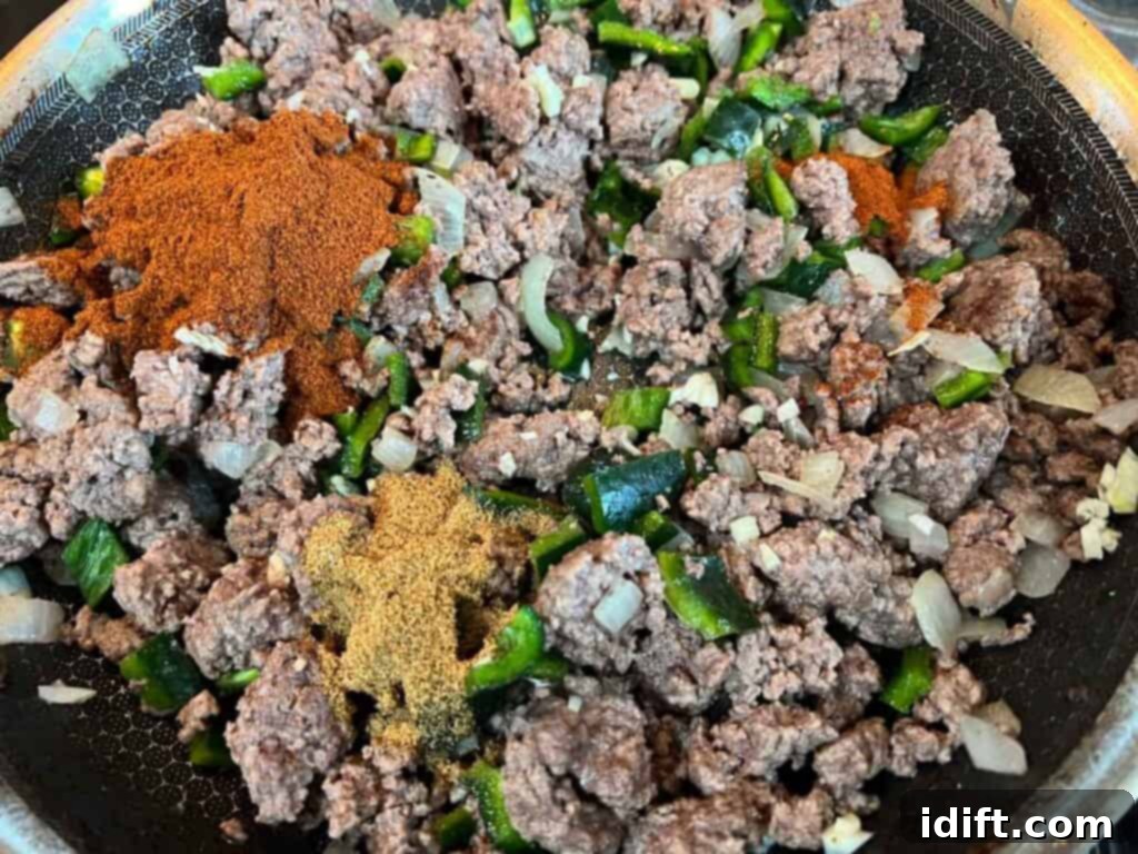 Adding spices and poblano chili to ground beef and onion mixture.