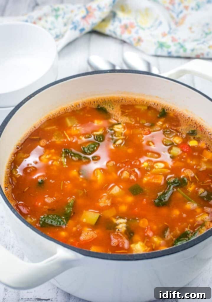 A large casserole dish filled with steaming hot Copycat Panera Bread’s 10 Vegetable Soup, showcasing vibrant vegetables.