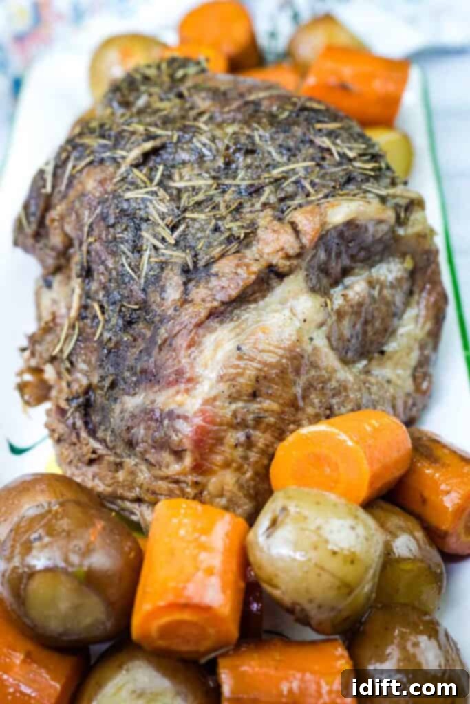 A long plate with a Slow Cooker Herb-Crusted Pork Roast with vegetables beside.