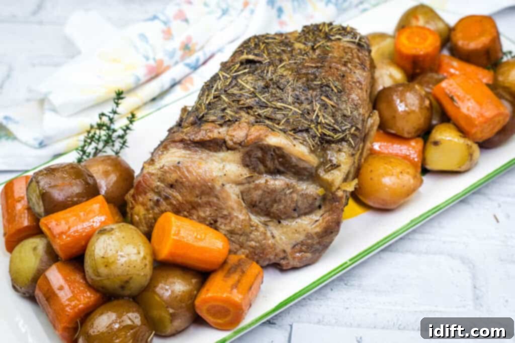 A plate of Slow Cooker Herb-Crusted Pork Roast with vegetables beside.