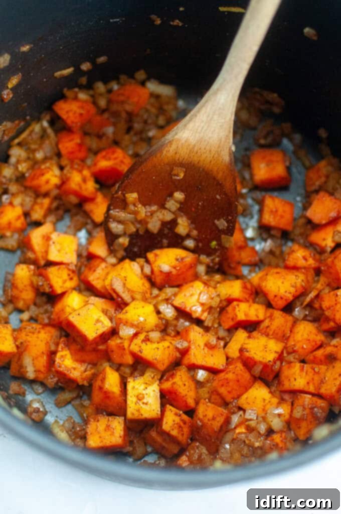 A close-up shot of the vegetables in the pot, thoroughly coated with aromatic spices, ready for the next step.