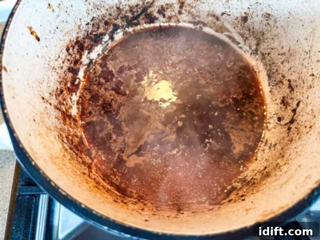 Pour in the red wine vinegar and red wine to deglaze the pot.