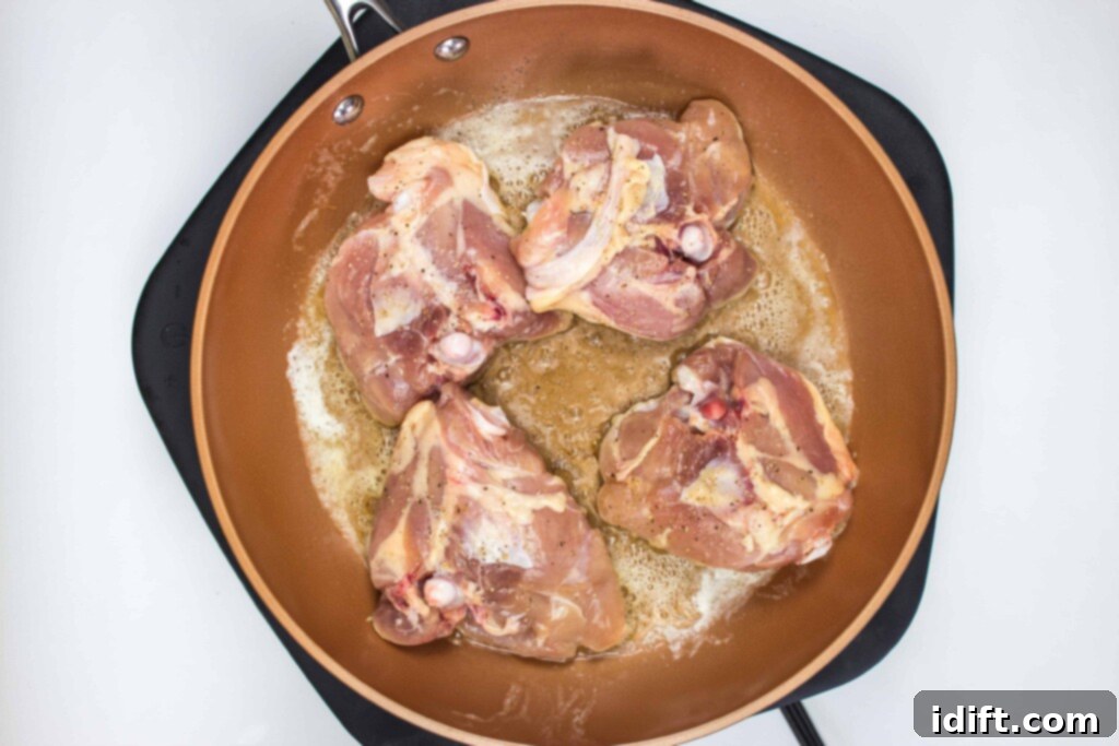 Roasted Garlic Chicken and Asparagus 6 Seasoned chicken thighs cooking skin-side down in a hot cast iron skillet, developing a golden-brown crust.