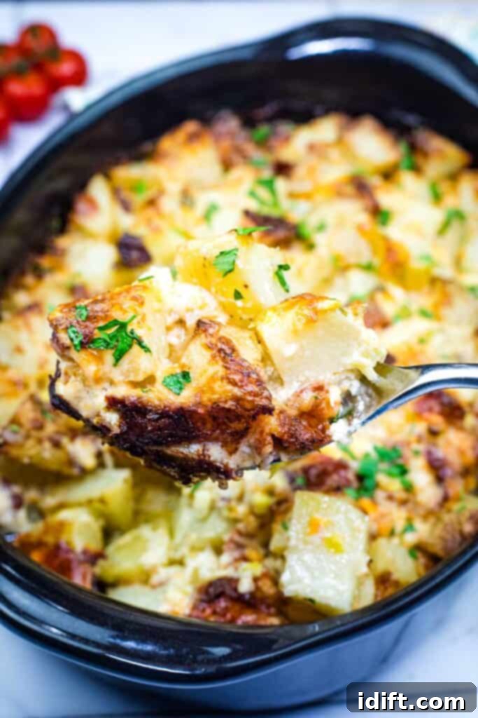 A spoon lifting a portion of Mississippi Mud Potatoes from a casserole dish, showcasing its cheesy, bacon-filled goodness.