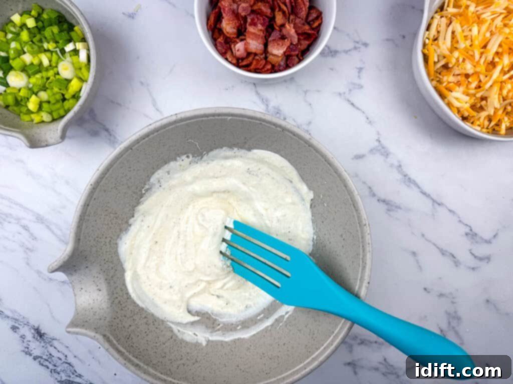 Close-up of a bowl where mayonnaise, sour cream, and spices are being mixed into a creamy sauce.