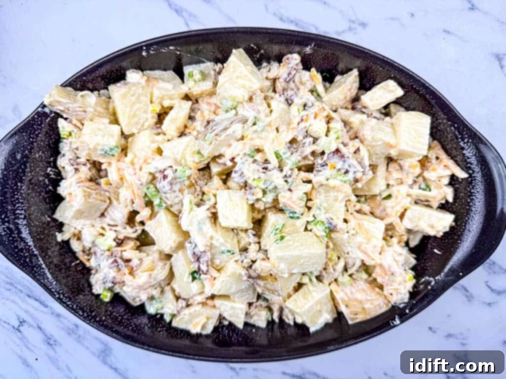 The combined potato mixture evenly spread in a 13x9-inch casserole dish, ready for baking.
