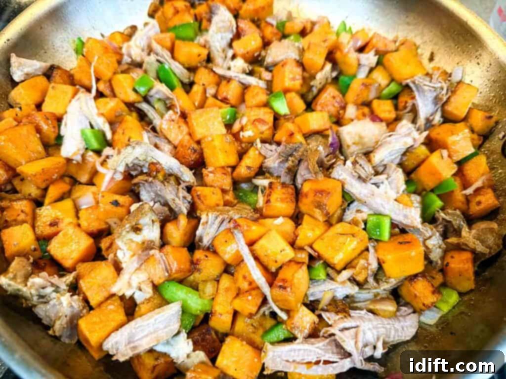 A cooking pan with pulled pork, chopped green bell pepper, chopped onion, minced garlic and sweet potatoes.