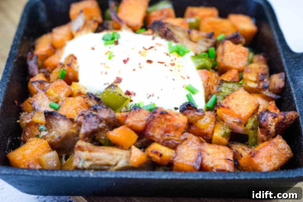 A serving of Sweet Potato Hash and Pulled Pork with heavy cream on top.