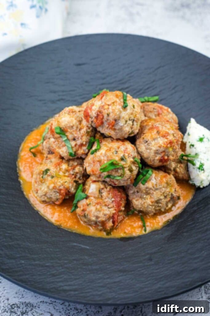 Cloud-Like Ricotta Meatballs with Rich Tomato Sauce 2 A serving of tender Ricotta Meatballs with rich Tomato Sauce, garnished with fresh basil, on a elegant black plate.