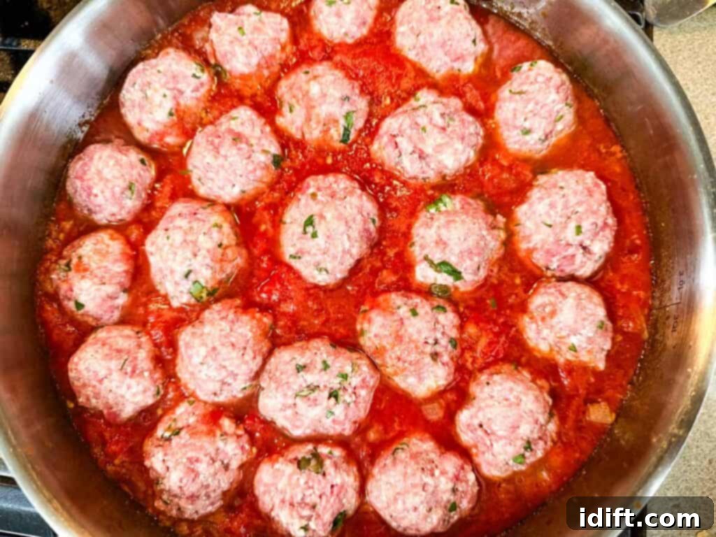 Cloud-Like Ricotta Meatballs with Rich Tomato Sauce 12 Raw meatballs carefully placed into a simmering pot of rich, red tomato sauce, ready to cook.