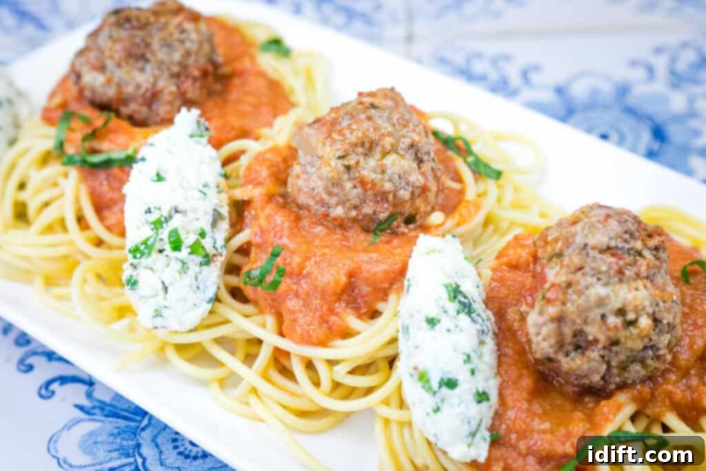 Cloud-Like Ricotta Meatballs with Rich Tomato Sauce 3 A white plate featuring perfectly cooked spaghetti generously topped with ricotta meatballs and a rich, vibrant tomato sauce, garnished with fresh herbs.
