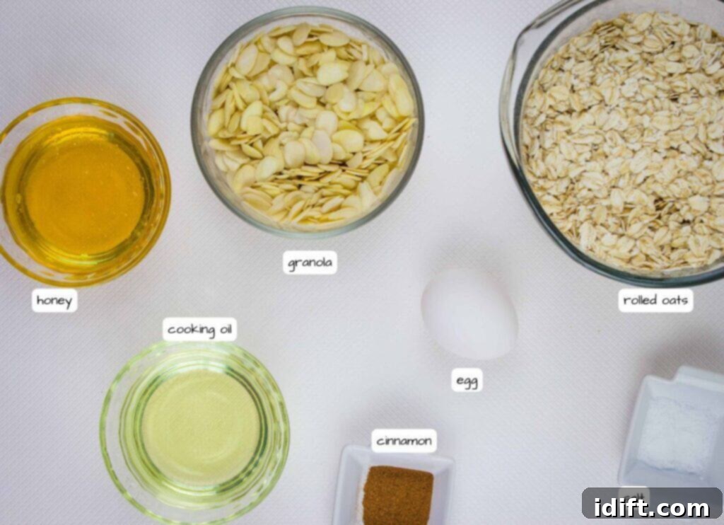 An overhead view displaying separate small bowls on a white surface, meticulously arranged with the individual ingredients for Honey Almond Granola: glistening honey, clear cooking oil, golden rolled oats, finely ground cinnamon, a pinch of salt, and a whole egg ready for use.