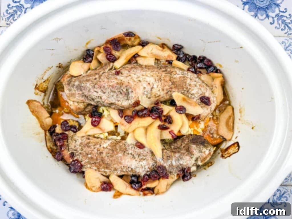 Cooked Pork Tenderloin with Sweet Potatoes & Apples in the slow cooker, ready to be removed.