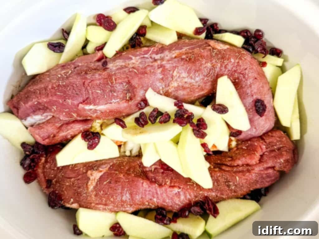 Apple wedges and dried cranberries nestled around the pork tenderloins in the slow cooker.