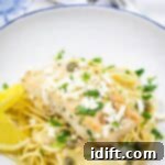 A pasta topped with a Skillet Chicken with Artichokes, Lemon, and Feta on a round plate.