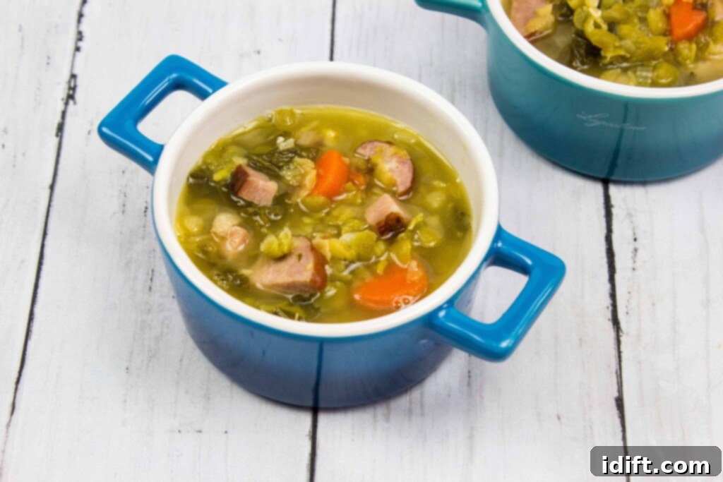 Two steaming bowls of Split Pea, Ham & Sausage Soup, garnished and served on a rustic wooden table, invitingly warm and hearty.