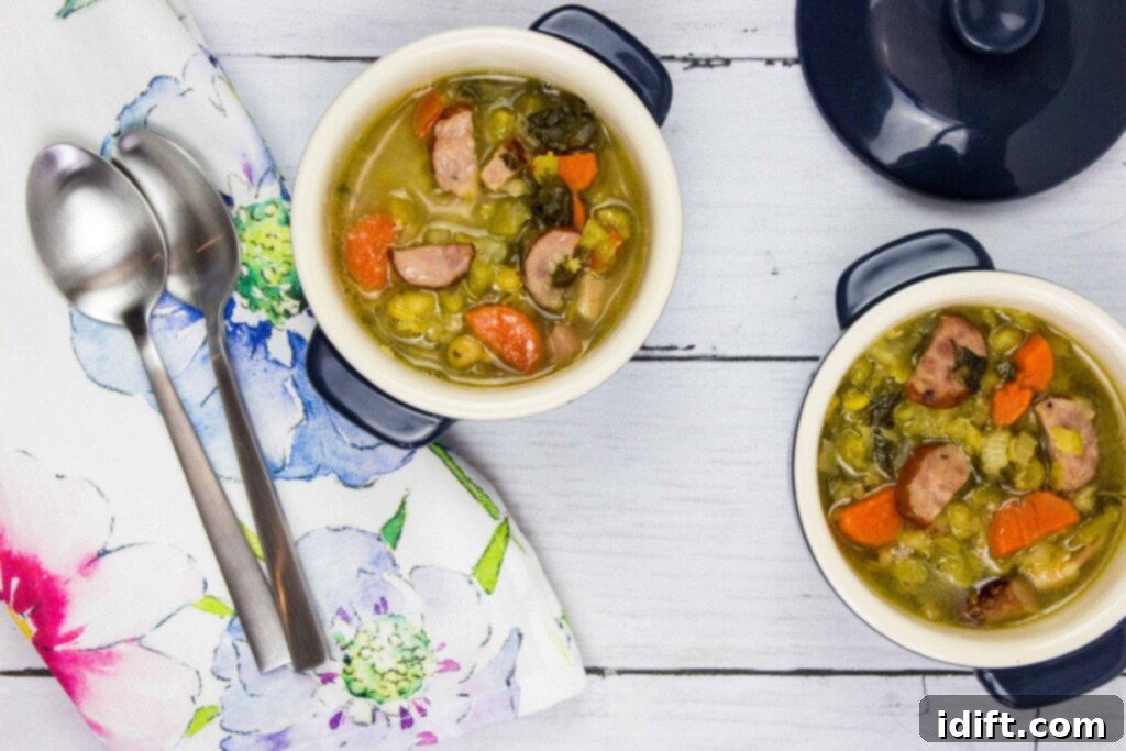 Two small, rustic bowls of Split Pea, Ham & Sausage Soup, each with a spoon, accompanied by a folded napkin, presented attractively on a wooden surface.