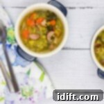 A small overhead shot of split pea, ham and sausage soup in two blue bowls with spoons and a napkin, perfect for a comfort meal.