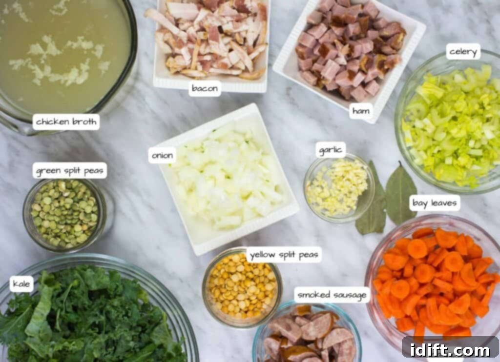 Various ingredients for Split Pea, Ham & Sausage Soup neatly arranged on a kitchen counter, including chicken broth, bacon strips, diced ham, chopped celery, carrots, a mix of green and yellow split peas, a whole onion, cloves of garlic, bay leaves, and fresh kale, with a package of smoked sausage.