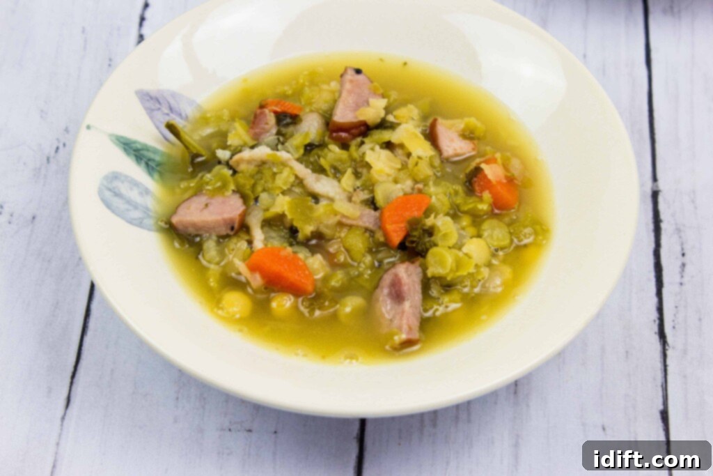 A single bowl of savory Split Pea, Ham & Sausage Soup, steaming gently, ready to be served and enjoyed as a comforting meal.