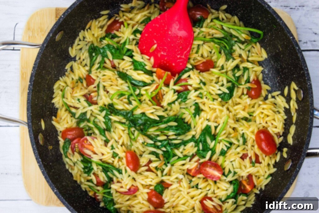 Velvety Spinach and Tomato Orzo 12 Cherry tomatoes and lemon juice being added to the creamy spinach orzo in the skillet, just before final mixing and serving.