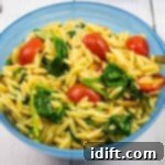 Velvety Spinach and Tomato Orzo 14 Creamy spinach orzo with tomatoes served in a rustic blue bowl, garnished and ready to eat.