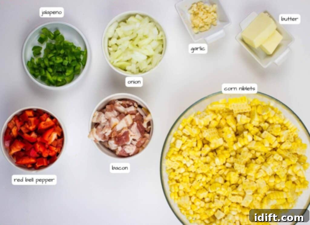 Top view of chopped jalapeno, onion, red bell pepper, bacon, corn niblets, garlic, and butter in separate bowls on a white surface, each labeled.