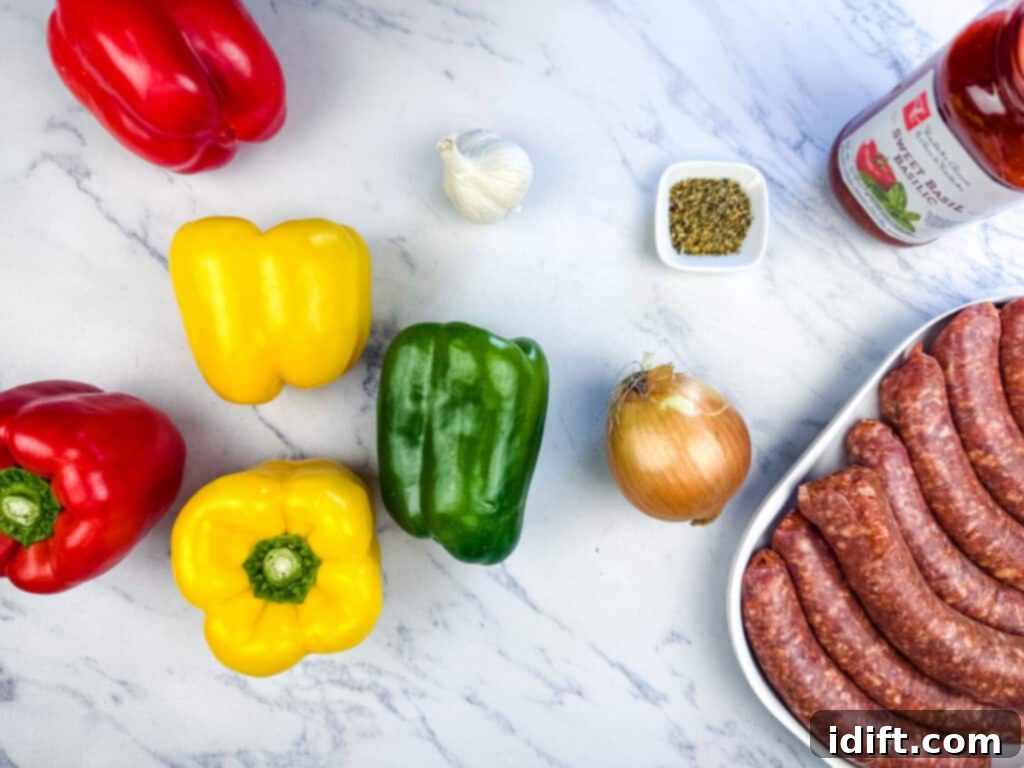 Assorted bell peppers, garlic, onion, oregano, a bottle of tomato sauce, and a tray of sausages are arranged on a marble surface, showcasing fresh ingredients.