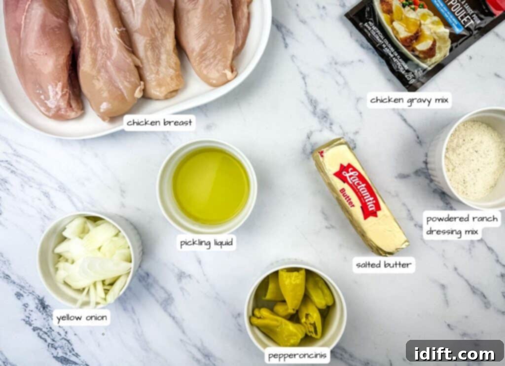 Ingredients for Slow Cooker Mississippi Chicken, neatly arranged: raw chicken breasts, sliced yellow onion, packets of gravy and ranch mix, jar of pepperoncini, and a stick of salted butter.