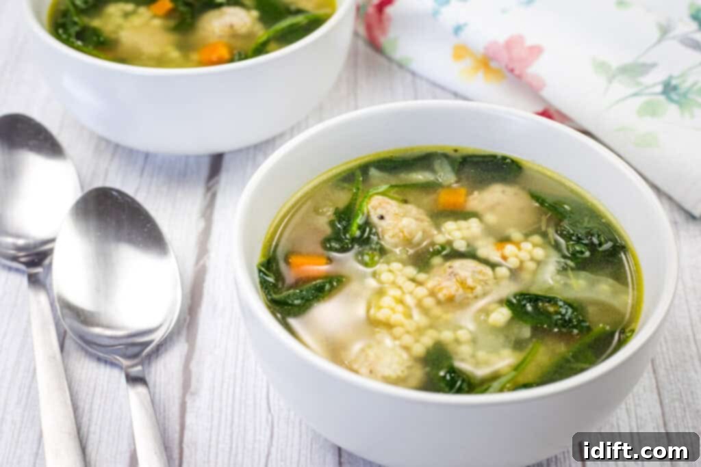 Two bowls of Italian Wedding Soup beside spoon and napkin.