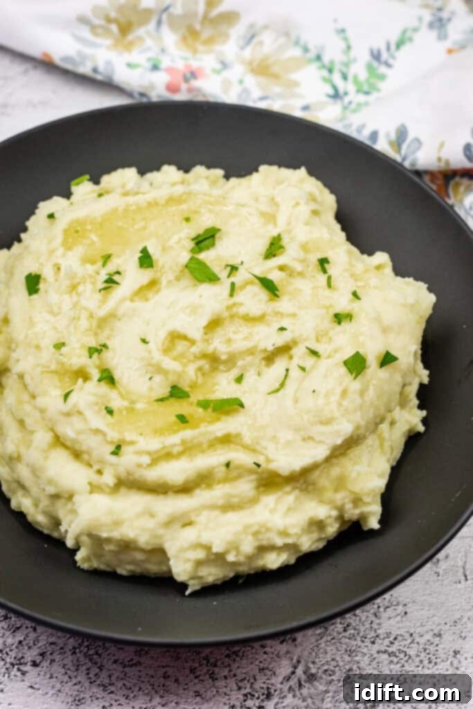 Mashed potatoes with cream cheese topped with melted butter and garnished with fresh parsley.