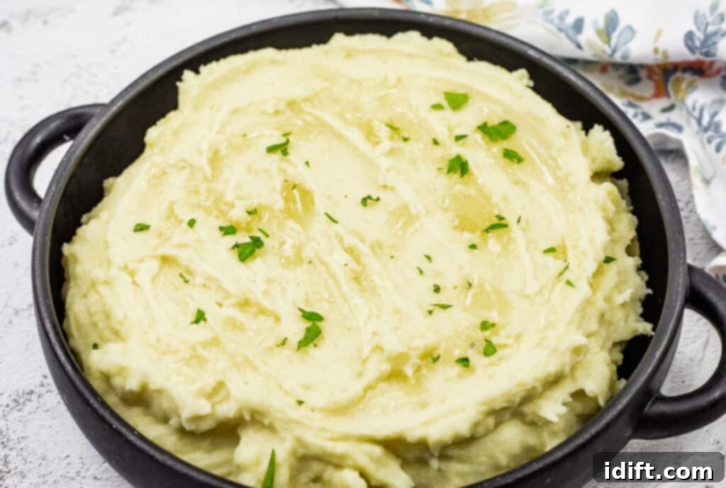 Mashed potatoes with cream cheese topped with melted butter and garnished with fresh parsley.