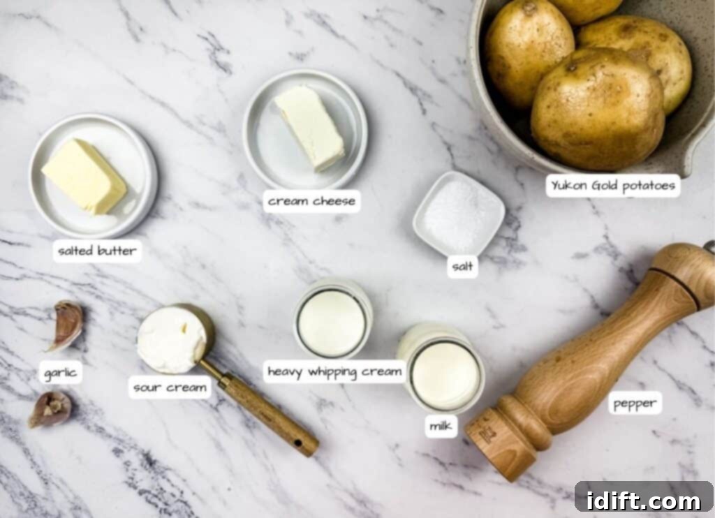 Mashed Potatoes with Cream Cheese ingredients on a marble surface, including butter, cream cheese, sour cream, garlic, milk, salt, pepper, and a bowl of potatoes with label.